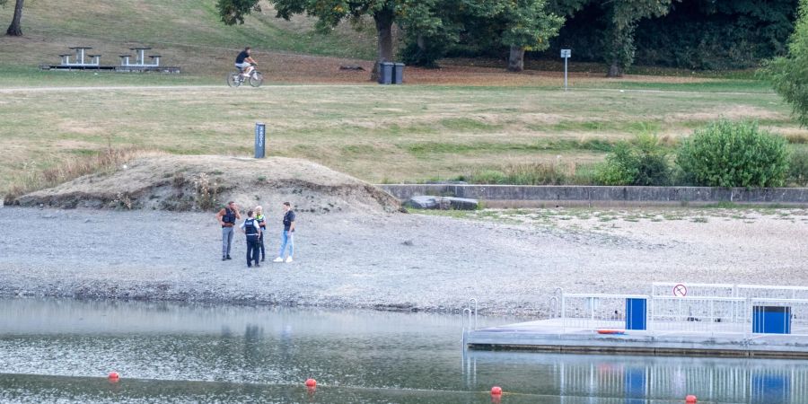 Polizisten stehen am Ufer des Eiserbachsees im Rurseezentrum. Nach einem Badeunfall in dem Badesee bei Aachen sind zwei Kinder gestorben.