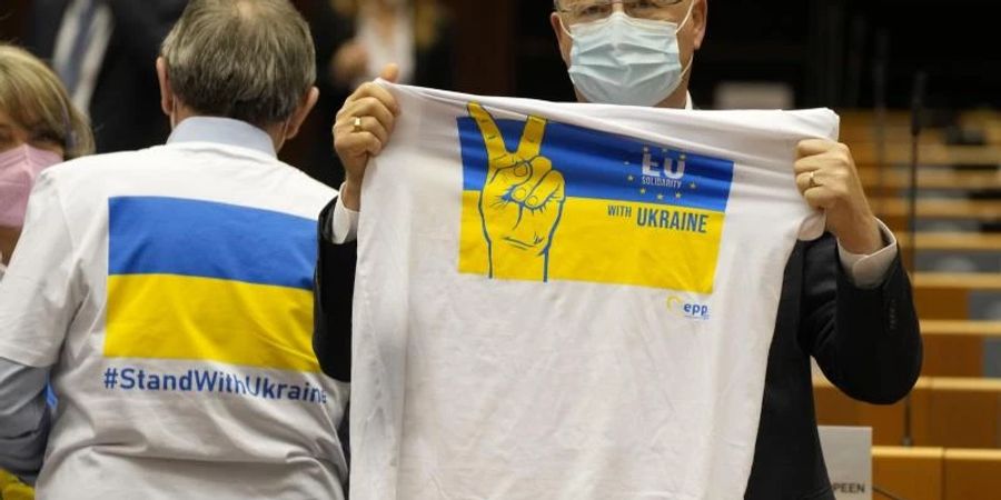 Ein Mitglied des Europäischen Parlaments hält ein T-Shirt in den Farben Blau und Gelb zur Unterstützung der Ukraine. Foto: Virginia Mayo/AP/dpa