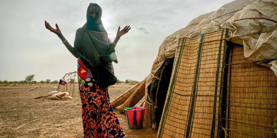 Eine Frau steht neben ihrer Hütte in einer von den Vereinten Nationen unterstützten Siedlung für Binnenflüchtlinge in Burkina Faso.