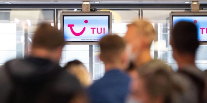Passagiere warten vor einem Tui-Schalter. Foto: Julian Stratenschulte/dpa tui