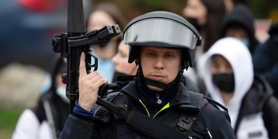 Ein schwerbewaffneter Polizist sichert Schüler, die aus der Schule geführt werden. Foto: Federico Gambarini/dpa