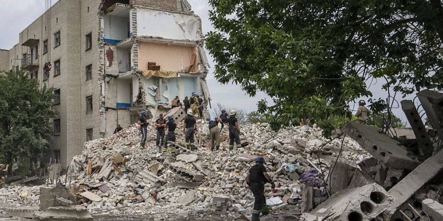 Rettungskräfte stehen auf den Trümmern eines Wohnblocks nach einem Raketeneinschlag in der Region Donezk in der Ostukraine. Foto: Nariman El-Mofty/AP/dpa