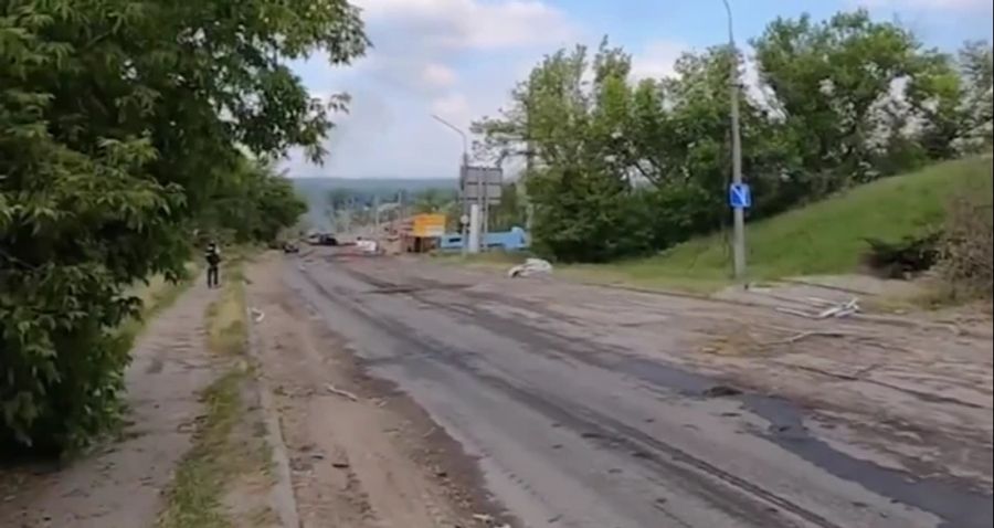 Eine Gruppe Journalisten steht im Donbass auf einer leeren Strasse.