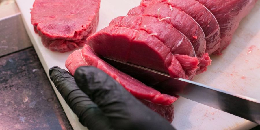 Ein Fleischer zeigt, wie er Steaks von einem Stück Rind quer zur Faser schneidet.