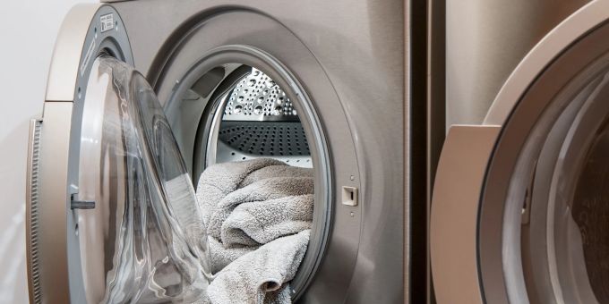 Eine silberfarbene Waschmaschine mit offener Tür aus der Wäsche herausschaut. Lassen Sie sich im alltäglichen Leben von Ihrem Umfeld helfen.