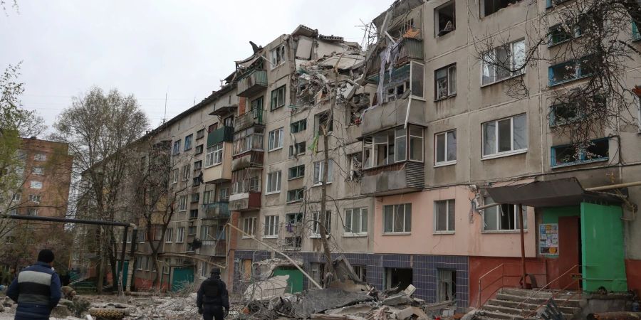 Menschen betrachten ein beschädigtes Gebäude nach einem Raketenangriff in der Stadt Slowjansk.