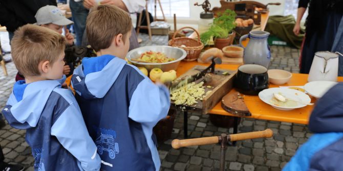 Kinder bedienen eine Obst-Zerkleinerungsmaschine.