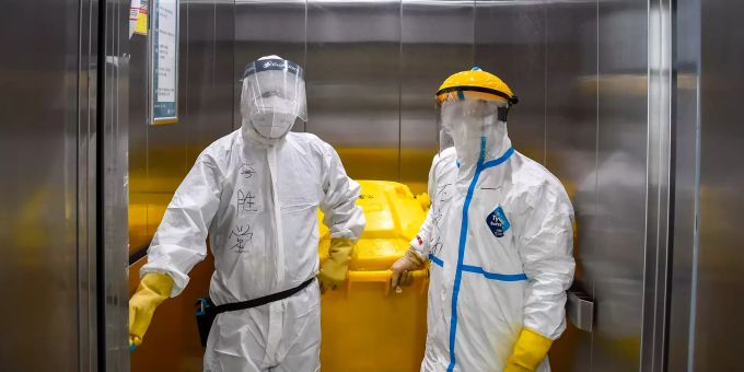 Zwei Mitarbeiter eines chinesischen Zentralkrankenhauses fahren mit Schutzkleidung in einem speziellen Fahrstuhl, um medizinischen Abfall zu entsorgen. Ganz so weit gehen die Vorgaben bei der hiesigen Abfallentsorgung noch nicht. Corona Abfall