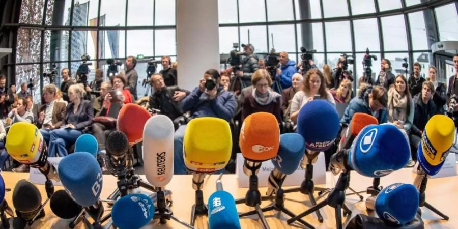Mikrofone von Fernseh- und Radiosendern stehen vor Beginn einer Pressekonferenz zu der Coronavirus-Infektion im bayerischen Staatsministerium für Gesundheit und Pflege. Foto: Peter Kneffel/dpa