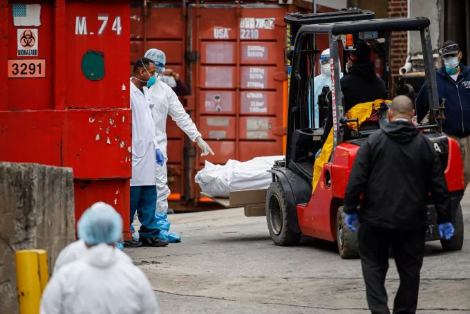 dpatopbilder - 31.03.2020, USA, New York: Eine mit Plastik umwickelte Leiche wird mit einem Gabelstapler von dem Brooklyn Hospital Center zu einem Kühlwagen, der zu einer temporären Leichenhalle umfunktioniert wurde, transportiert. Foto: John Minchillo/AP/dpa +++ dpa-Bildfunk +++ Coronavirus - USA