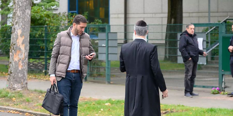 Philipp Stricharz (l), erster Vorsitzender der jüdischen Gemeinde Hamburg, steht mit Shlomo Bistritzky, Landesrabbiner von Hamburg, vor der Synagoge und schaut auf sein Handy. Ein Mann im Tarnanzug hatte einen Studenten mit einem Spaten angegriffen. Foto: Jonas Walzberg/dpa