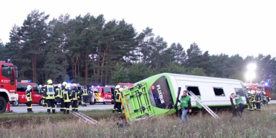 Feuerwehrleute stehen an der Autobahn A24 neben einem verunglückten Fernbus. Bei dem Fernbusunglück hat es am frühen Morgen nach Polizeiangaben 31 Verletzte gegeben. Foto: Ralf Drefin/dpa