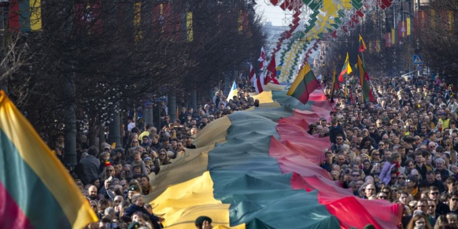 dpatopbilder - ARCHIV - Menschen tragen eine riesige litauische Flagge während einer Feier zum 35. Jahrestag der Unabhängigkeit Litauens von der Sowjetunion. Foto: Mindaugas Kulbis/AP...