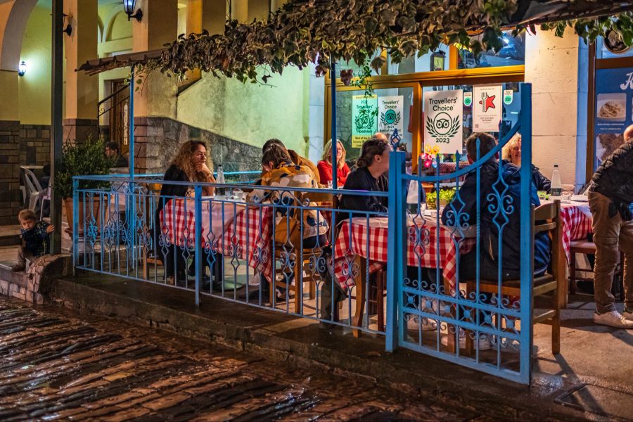 Alte Strasse mit Cafétischen und Touristen beim Abendessen. Strassenrestaurants in Gjirokaster in der Sommernacht Albanien.