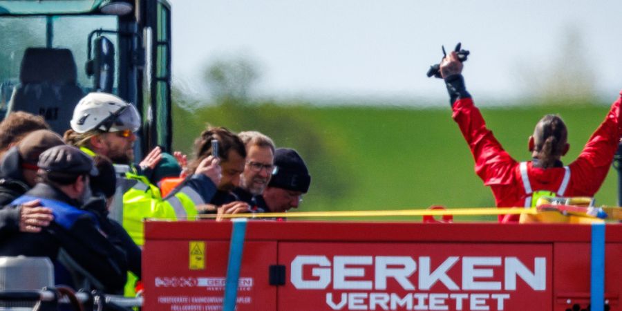 dpatopbilder - Helfer feiern auf dem Transportschiff, nachdem der gestrandete Buckelwal vor der Insel Poel mit Gurten in den Lastkahn gezogen wurde. Foto: Jens Büttner/dpa