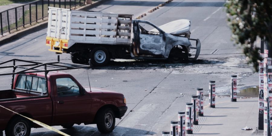 Ein Fahrzeug steht ausgebrannt auf einer Straße in Guadalajara. Nach dem Tod von Mexikos mächtigstem Drogenboss wurden in mehreren Bundesstaaten Straßen mit brennenden Autos, Lastwag...