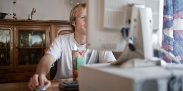 Arbeit: junger Mann sitzt vor dem Computer und bewirbt sich.