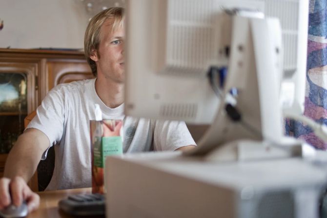 Arbeit: junger Mann sitzt vor dem Computer und bewirbt sich.