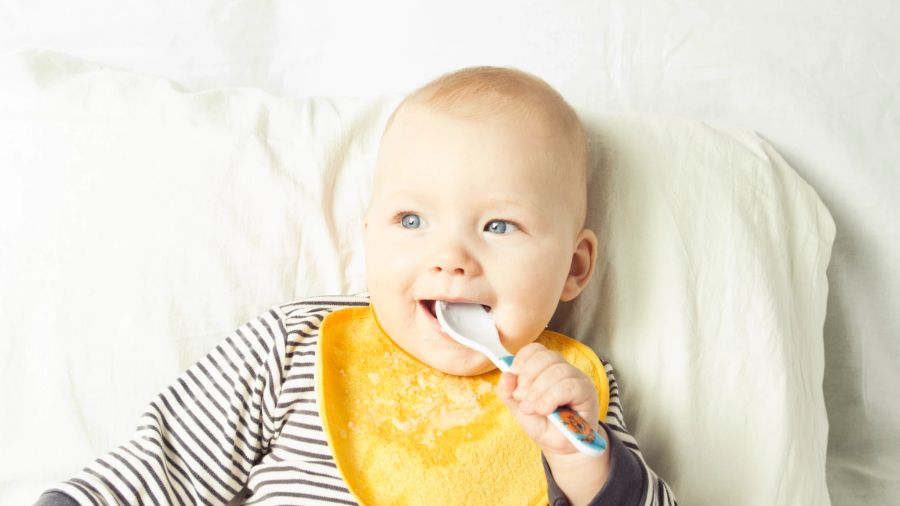 süsses grinsendes baby mit löffel im mund