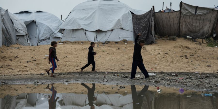 Vertriebene palästinensische Kinder laufen nach einem Unwetter durch ein Zeltlager in Gaza-Stadt. Foto: Jehad Alshrafi/AP/dpa