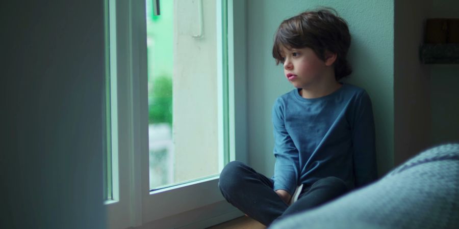 trauriger Junge auf der Fensterbank