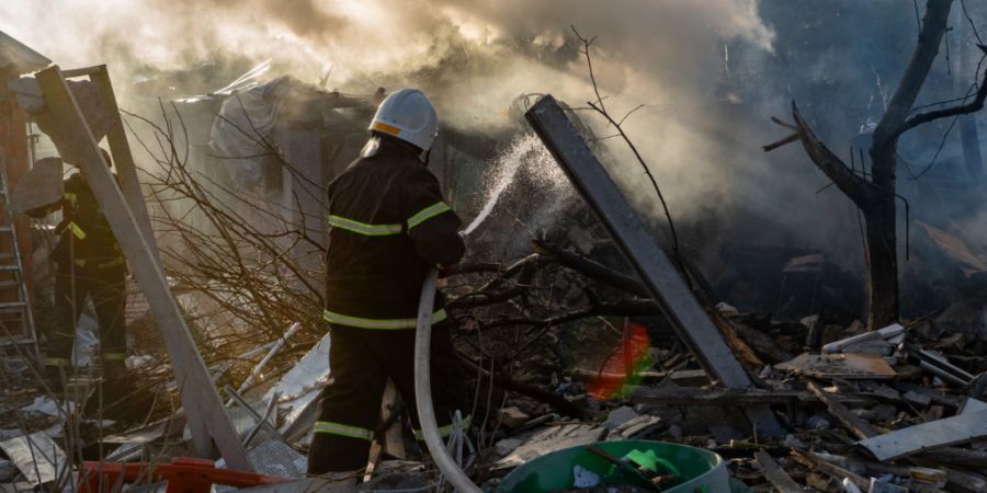 Eine Rettungskraft löscht einen Brand in einem Wohnhaus, das durch einen Luftangriff zerstört wurde. Foto: Andrii Marienko/AP/dpa/Archivbild