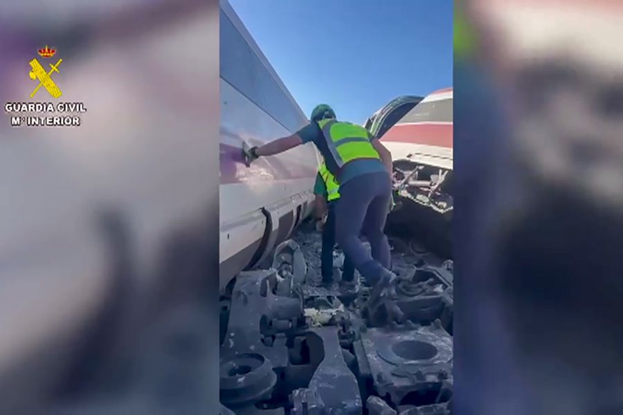 Ein Beamter der Guardia Civil klettert zwischen den beschädigten Waggons durch Trümmer.