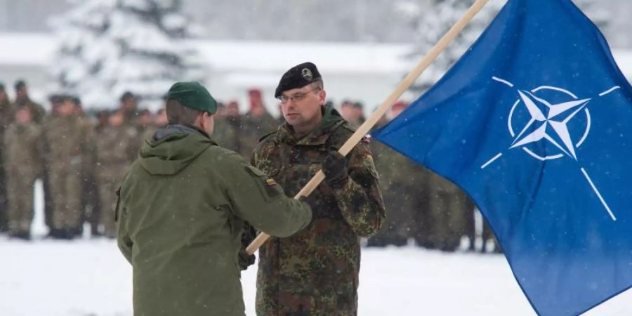 Der Brigadeführer von Iron Wolf, Steponauvicius Mindaugas, übergibt beim Übergabeappell die Natoflagge an Peter Papenbroock, Bundeswehr-Oberstleutnant und neuer Kommandeur der EFP Battlegroup in Litauen. Foto: Arne Immanuel Bänsch