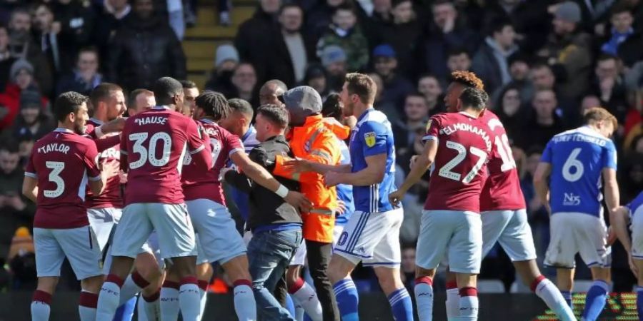 Aston-Villa-Profi Jack Grealish (r) sitzt nach dem Fan-Angriff (8.v.l) auf dem Rasen. Foto: Nick Potts/PA Wire