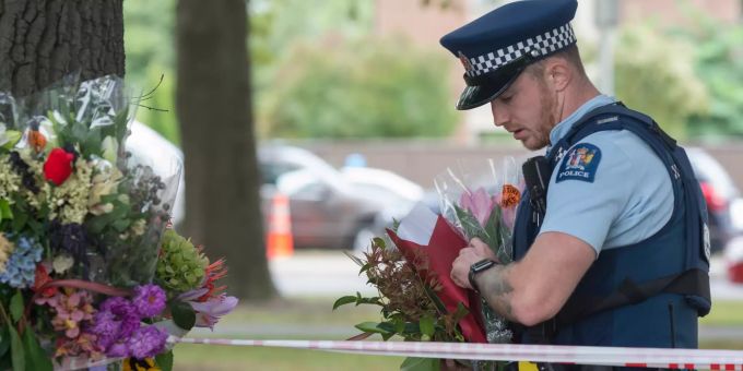 Ein Polizist hält Blumen für die Opfer des rassistisch motivierten Anschlags in Christchurch. Gedenken an Opfer des Terroranschlags von Neuseeland