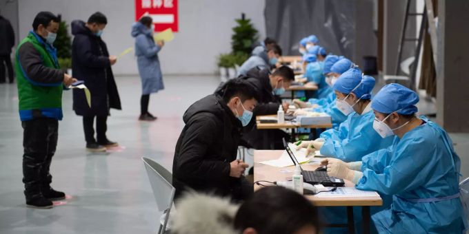 Einwohner Pekings füllen Formulare aus, bevor sie ihre Corona-Impfung an einer temporären Impfstelle erhalten. Coronavirus - China