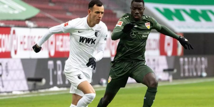 Augsburgs Iago (l) und Stuttgarts Silas Wamangituka im Zweikampf um den Ball. Foto: Matthias Balk/dpa