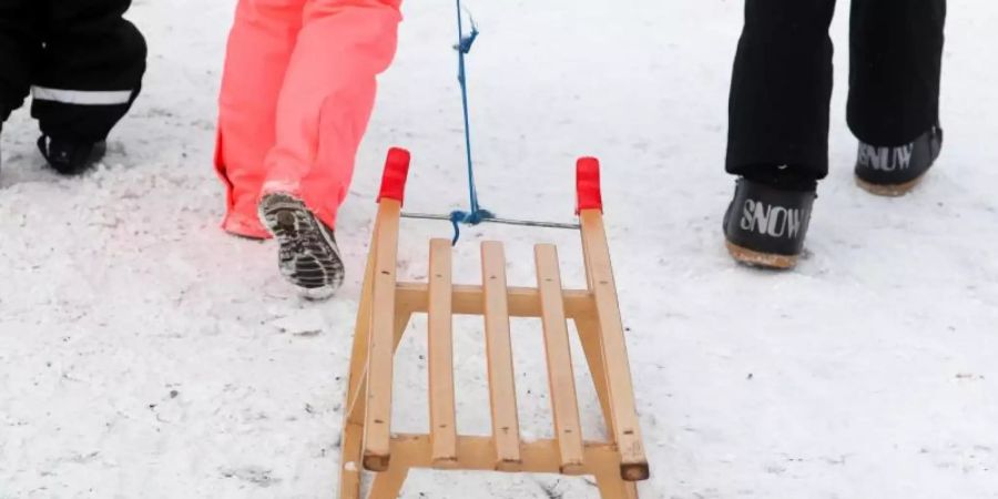 Winterurlauber gehen mit einem Schlitten zu einer Rodelbahn. NRW erwägt erneut eine Verlängerung der Winterferien. Foto: Jan Woitas/dpa-Zentralbild/ZB