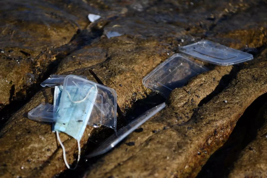 Angespülte medizinische Mundschutze und Plastikbehälter liegen an der Küste von Port Botany.