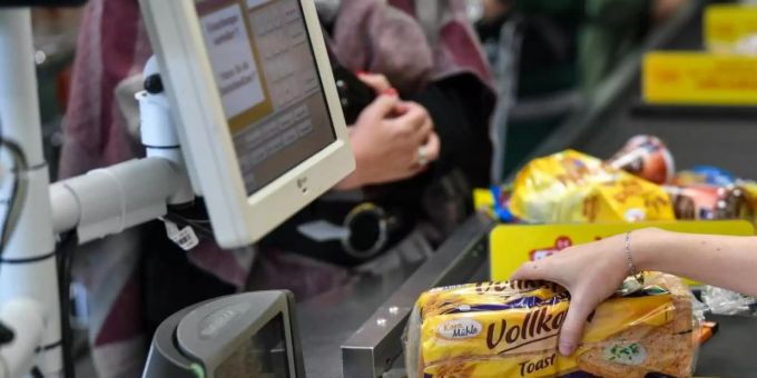 Eine Kassiererin an der Kasse beim Supermarkt. Inflation