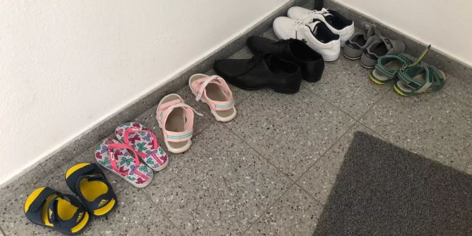 Die Schuhe der beiden Kinder und des Vaters vor der Wohnungstür.