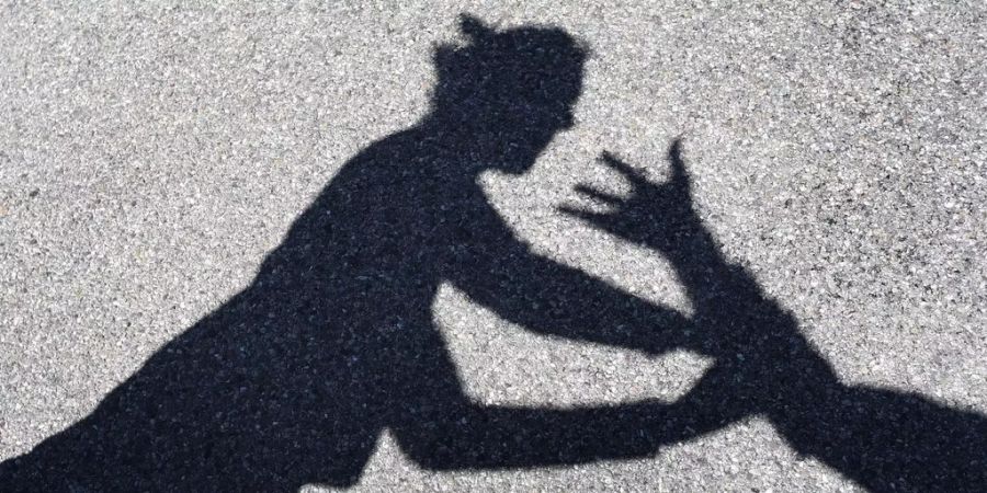 Ein Mann greift nach einer Frau, man sieht nur die Schatten.