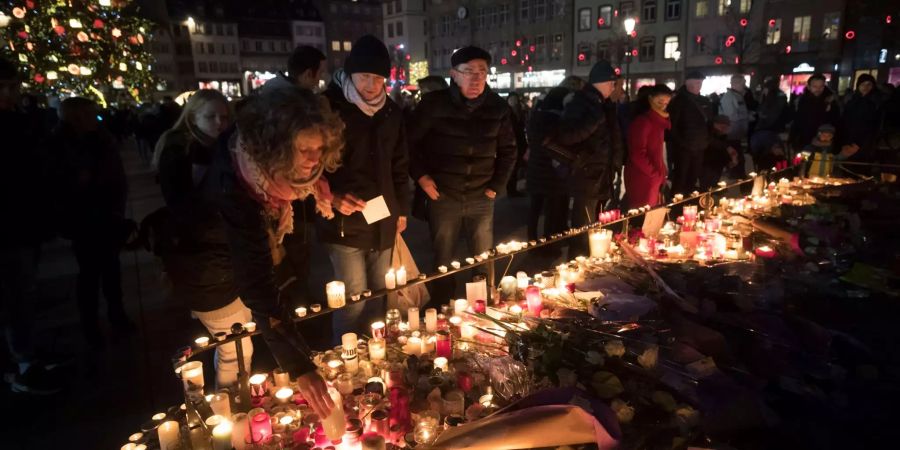 Trauernde stellen Kerzen auf, um den Opfern des Anschlags auf dem Weihnachtsmarkt in Strassburg zu gedenken.