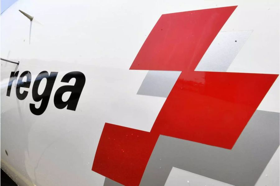 Seite eines Rega Helikopters mit dem Rega Schiftzug und Logo - Keystone