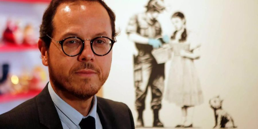 Artcurial-Beauftragter Arnaud Oliveux posiert vor einem Banksy-Werk.