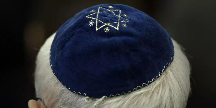 Ein Mann trägt in der Synagoge eine Kippa mit einem aufgenähtem Stern.