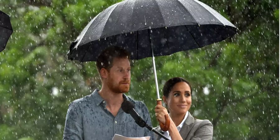 Prinz Harry spricht neben Herzogin Meghan, die während eines Regenschauers einen Schirm hält, zur Gemeinde von Dubbo (AUS).