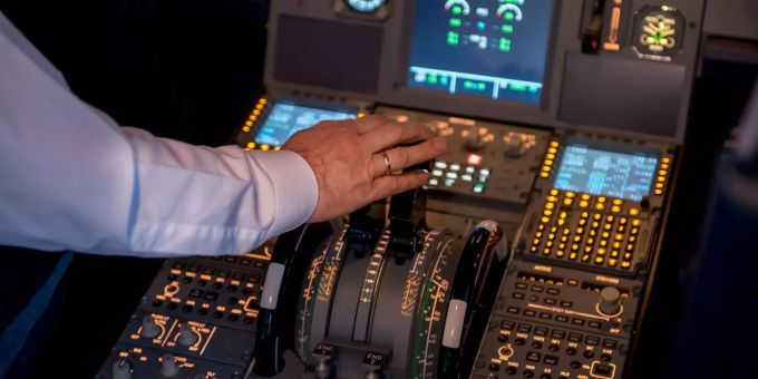 Ein Pilot steuert im Cockpit ein Flugzeug. Cockpit