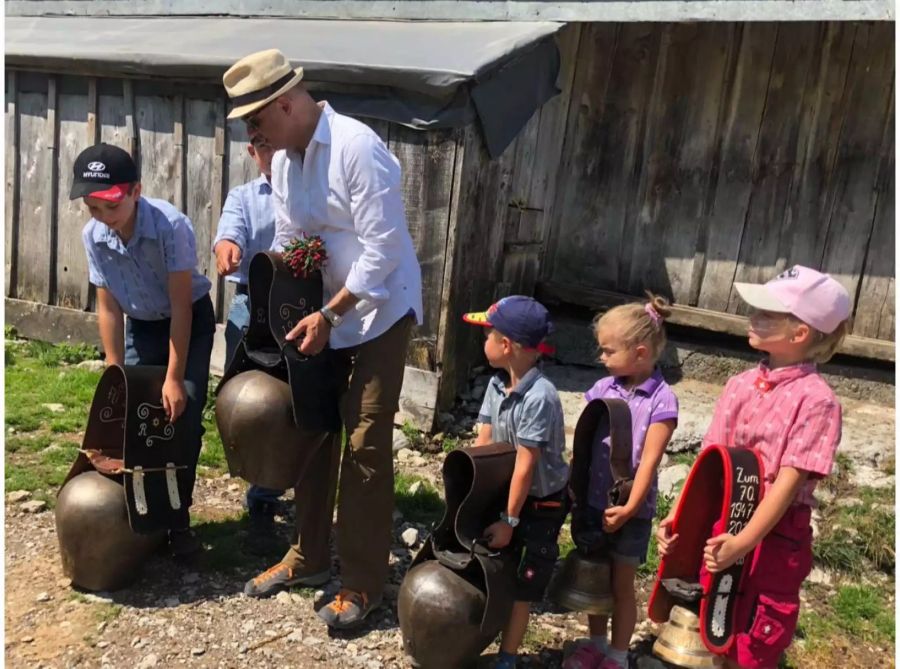 Bundespräsident Alain Berset ganz Bodenständig: Auf der Wanderung durch die Freiburger Alpen lernt er von Kindern, wie man Kuhglocken zum Klingen bringt.