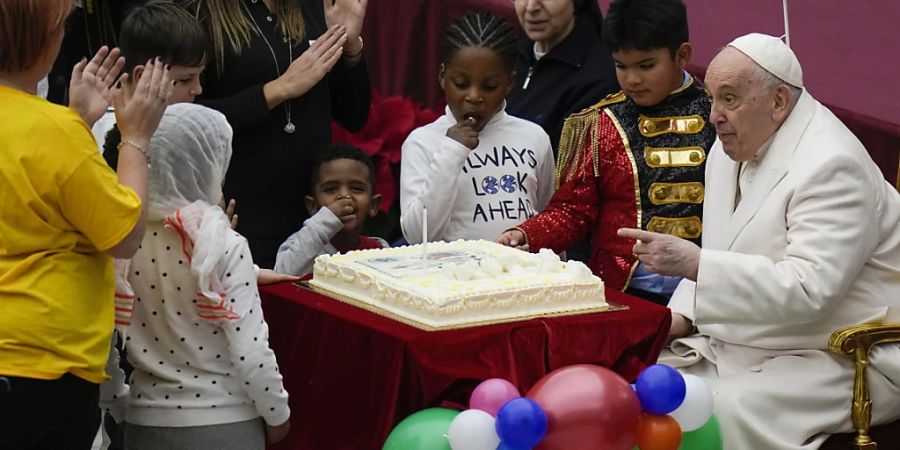 Papst Franziskus wird ein Kuchen angeboten, während er in der Paul VI.-Halle im Vatikan seinen Geburtstag mit Kindern feiert. Foto: Alessandra Tarantino/AP/dpa