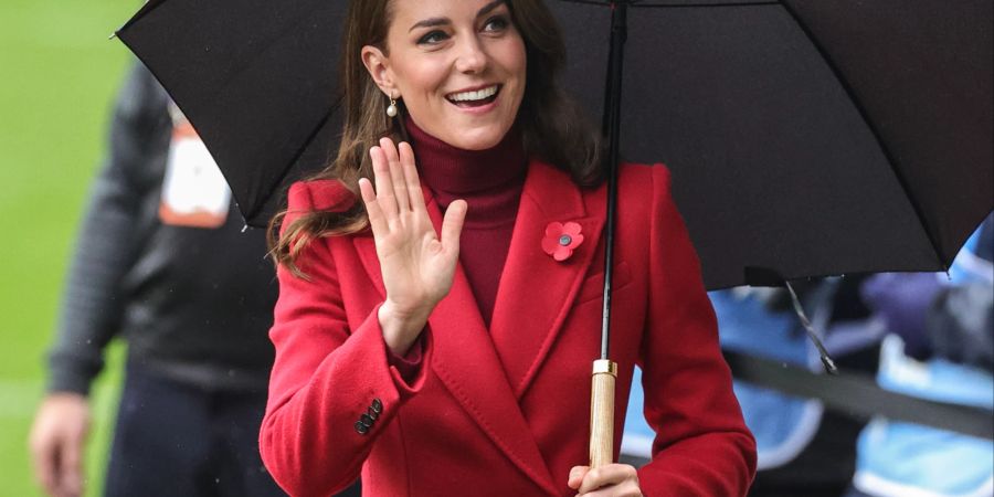 Kate Middleton, Prinzessin, Herzogin von Wales im roten Mantel mit regenschirm.