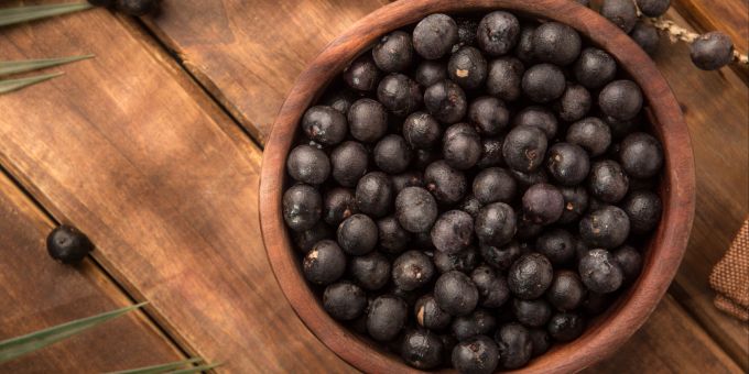 Die gesunde Beere kommt ursprünglich aus dem Amazonas. Schale Açai-Beeren Holztisch.