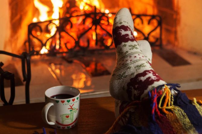 hochgelegte füsse vor kaminfeuer, tasse glühwein