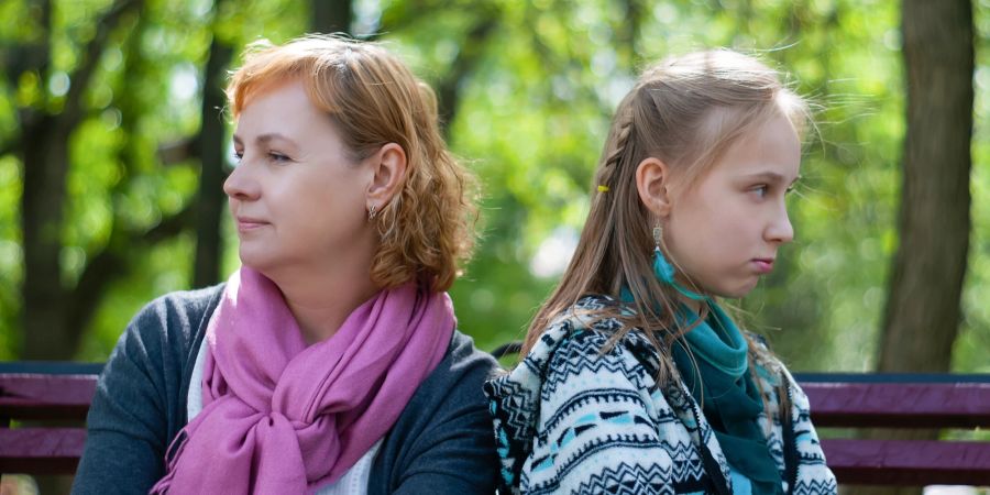 Mutter und beleidigtes Mädchen auf Sitzbank