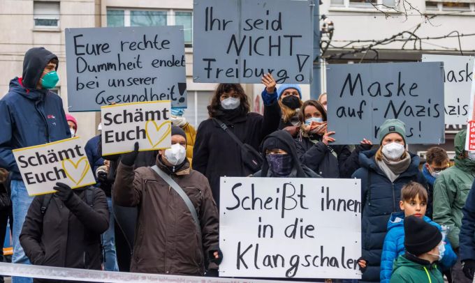 Gegendemonstranten der «Querdenker»-Demo stehen mit verschiedenen Schildern am Rande der Demonstration. Corona demo